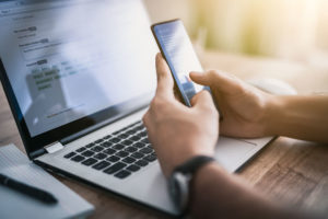 man using phone and laptop