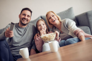 Smiling young family watching TV together