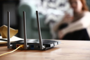 Modern wi-fi router on wooden table in room